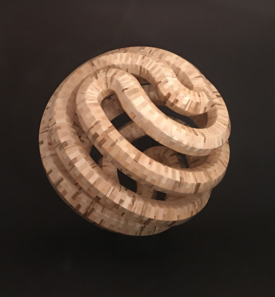 blond wood in geometric patterns carved into a sphere using segmented wood turning